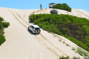 White colored 4WD on a sand track.