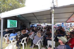 Group of people sitting on big tent and listening to a 4WD forums.