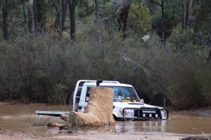 White 4WD truck travelling/crossing on a watery track.